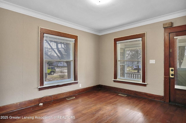 spare room with ornamental molding, baseboards, visible vents, and hardwood / wood-style floors