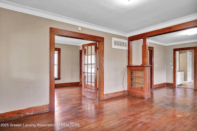 empty room with wood-type flooring, visible vents, and crown molding