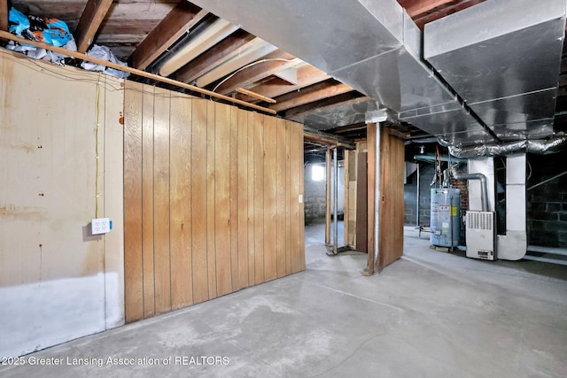 unfinished basement with water heater, wood walls, and heating unit