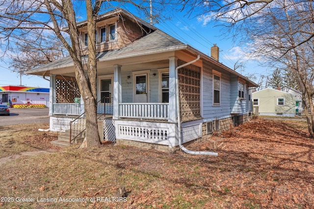 view of front of home featuring covered porch, a chimney, and roof with shingles