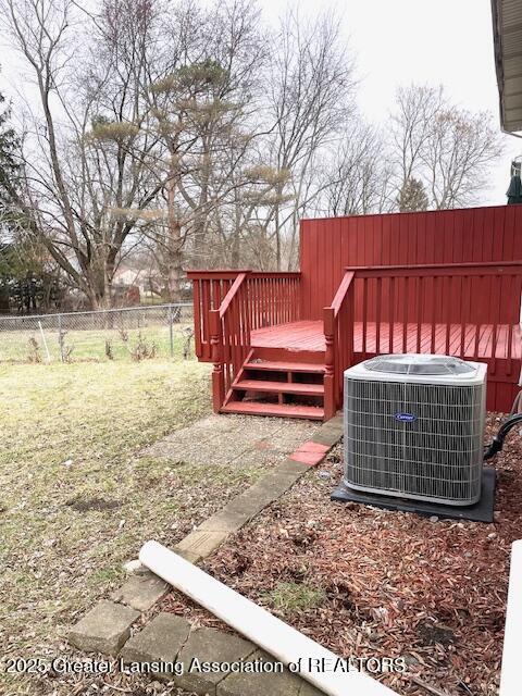 view of yard with fence, a deck, and central air condition unit