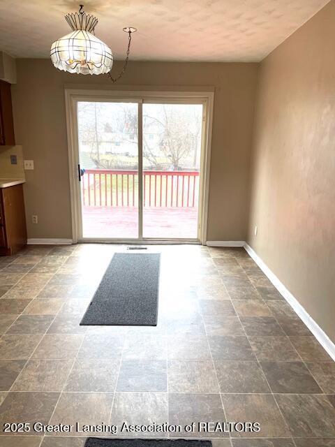 doorway to outside featuring baseboards, stone finish floor, and a healthy amount of sunlight