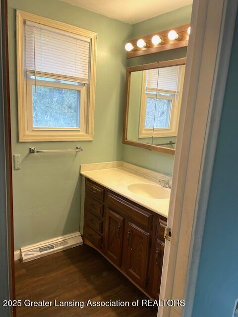 bathroom with visible vents, wood finished floors, vanity, and baseboards