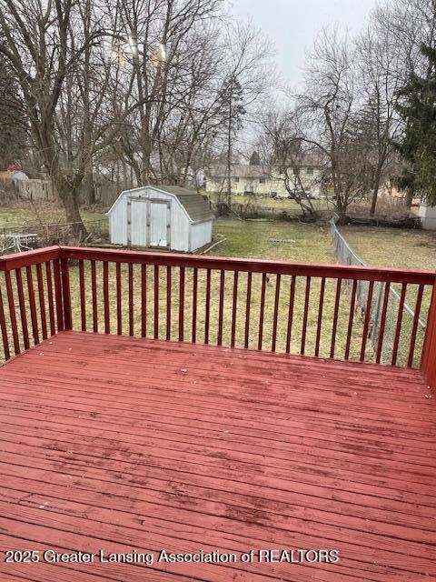 wooden deck featuring a storage shed, a yard, and an outbuilding