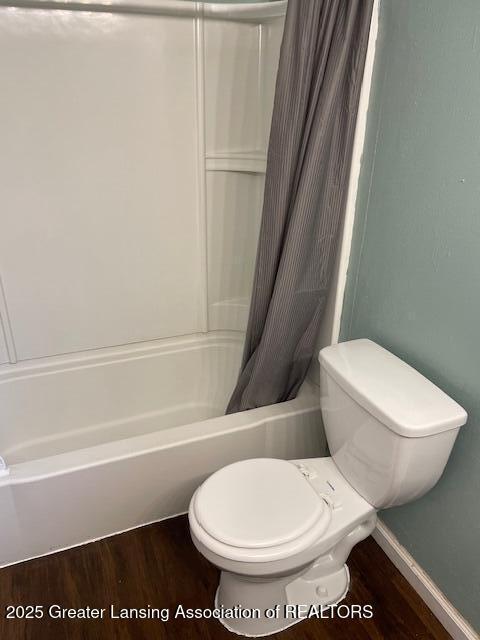 full bath with baseboards, wood finished floors, toilet, and shower / tub combo with curtain