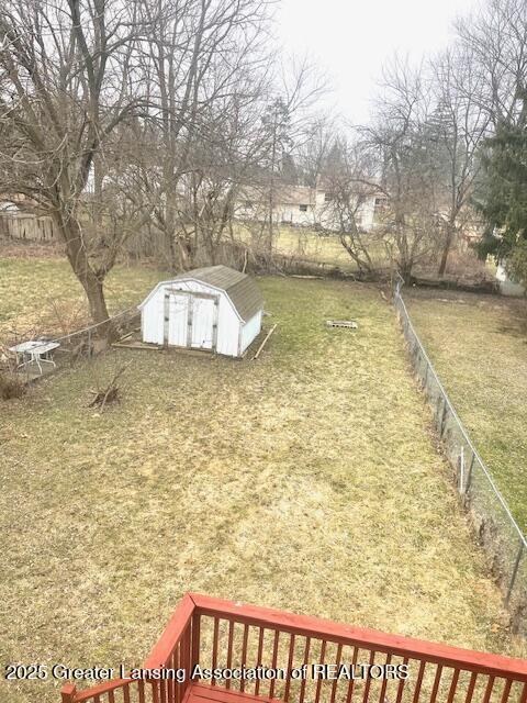 view of yard with an outdoor structure, fence, and a storage unit