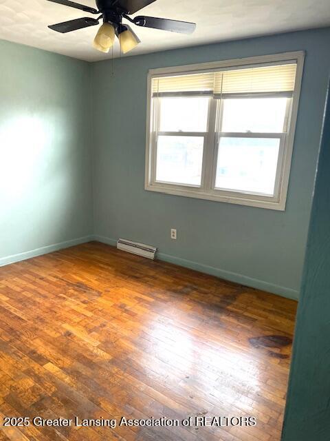 unfurnished room with a ceiling fan, a baseboard radiator, baseboards, and hardwood / wood-style floors