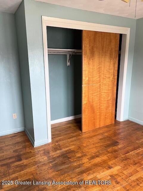 unfurnished bedroom with a closet, baseboards, and wood finished floors