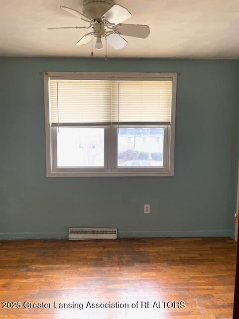 unfurnished room featuring a baseboard radiator, wood finished floors, a ceiling fan, and baseboards