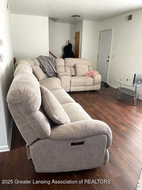 living area with wood finished floors, visible vents, and baseboards