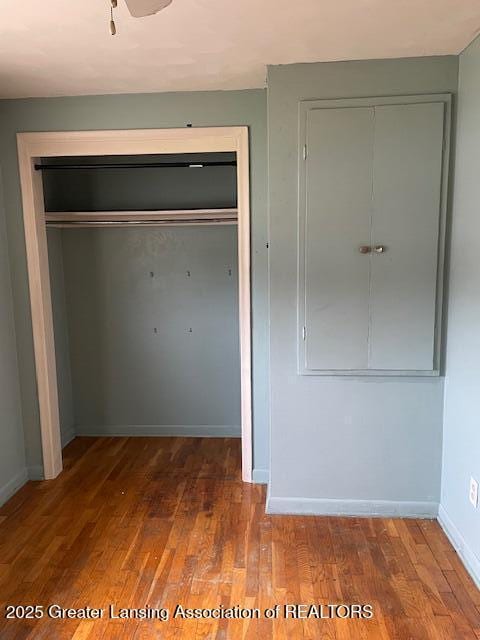 unfurnished bedroom featuring a closet, wood finished floors, and baseboards