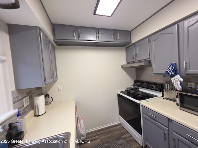 kitchen featuring range with electric stovetop, light countertops, stainless steel microwave, gray cabinetry, and under cabinet range hood