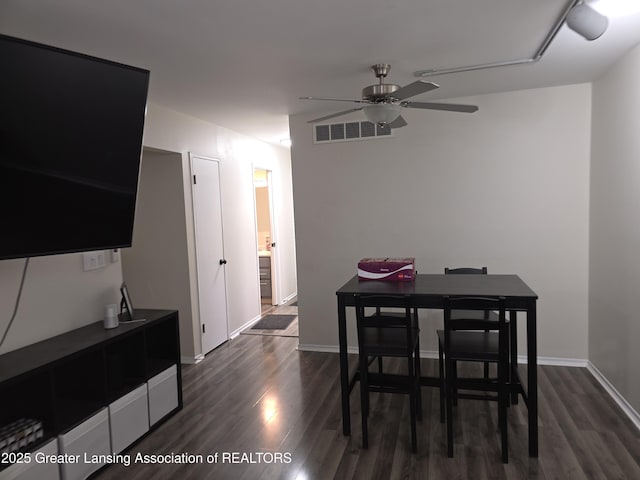 dining space with a ceiling fan, visible vents, dark wood finished floors, and baseboards