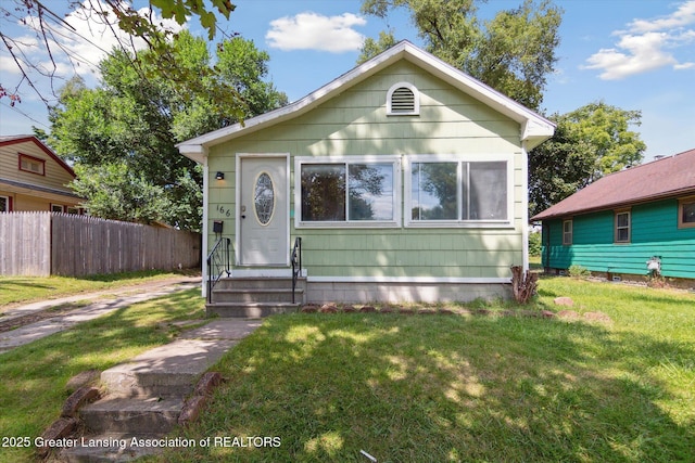 bungalow featuring entry steps, a front lawn, and fence