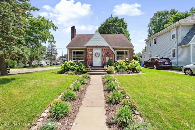 view of front of property with a front yard, a shingled roof, a chimney, and brick siding