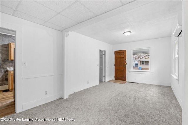 carpeted empty room with visible vents and a drop ceiling