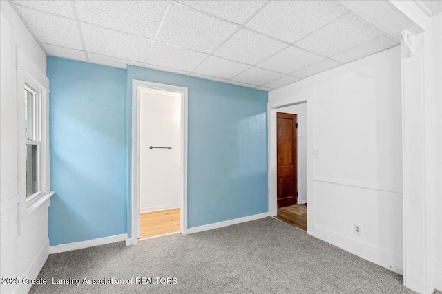 unfurnished room with baseboards, a drop ceiling, and carpet flooring