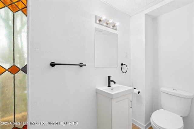 bathroom with baseboards, vanity, and toilet