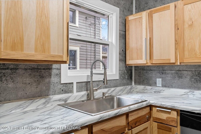 kitchen featuring dishwashing machine, light brown cabinets, light countertops, and a sink