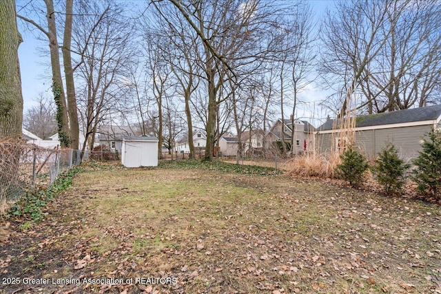 view of yard with a residential view, a fenced backyard, an outdoor structure, and a shed