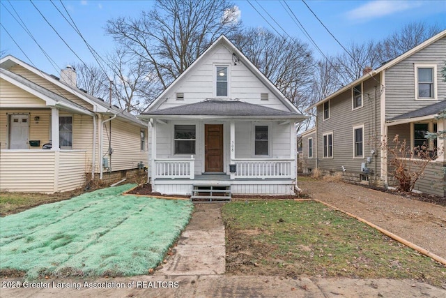 view of front of house with roof with shingles, a porch, and a front lawn