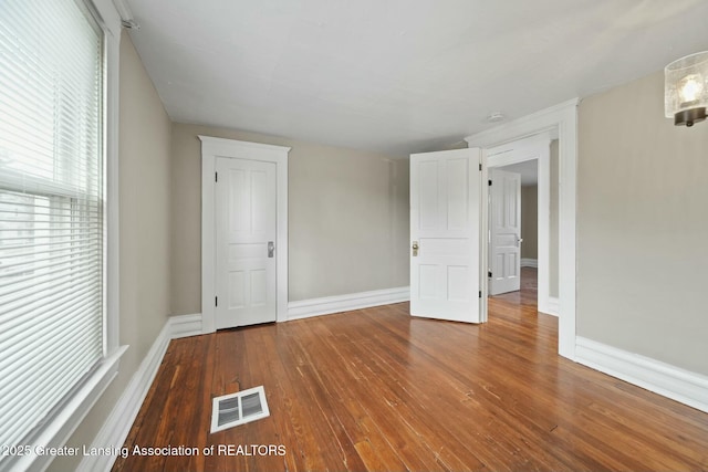 unfurnished room with baseboards, visible vents, and hardwood / wood-style floors