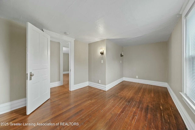 spare room featuring baseboards and hardwood / wood-style flooring