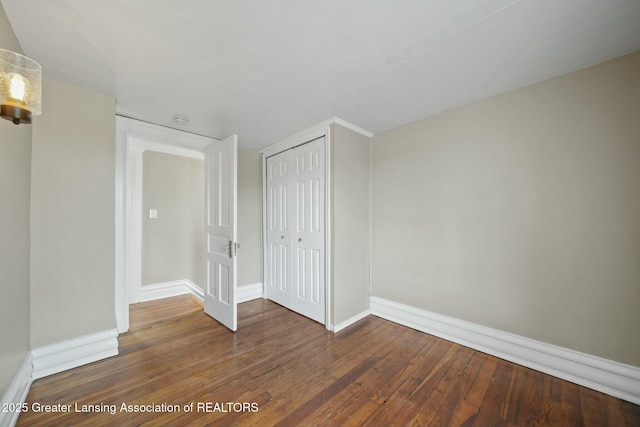 unfurnished room with baseboards and hardwood / wood-style flooring