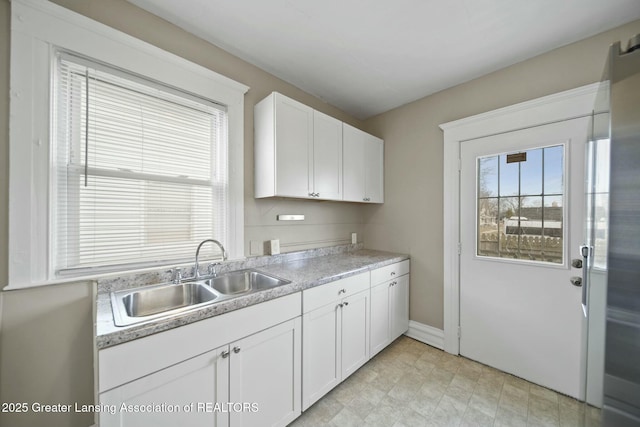 kitchen with light countertops, a sink, a wealth of natural light, and white cabinets