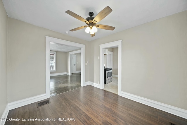 spare room with baseboards, visible vents, ceiling fan, and wood finished floors