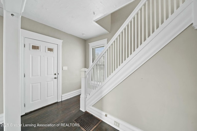 entrance foyer with stairs, dark wood-style flooring, visible vents, and baseboards