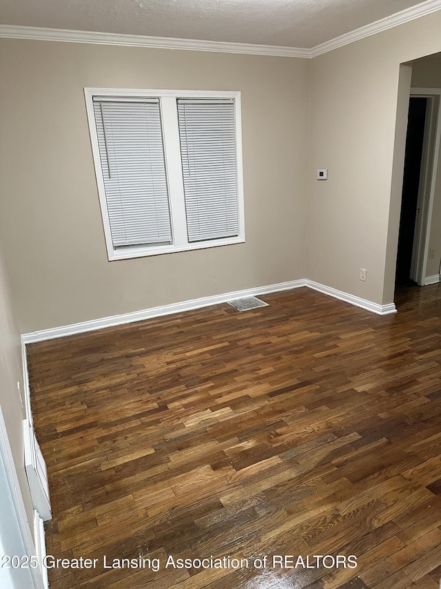 unfurnished room with ornamental molding, dark wood finished floors, visible vents, and baseboards