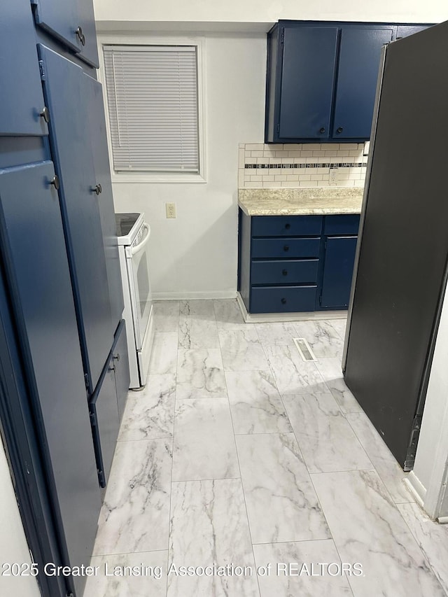 kitchen with electric stove, marble finish floor, blue cabinetry, backsplash, and freestanding refrigerator