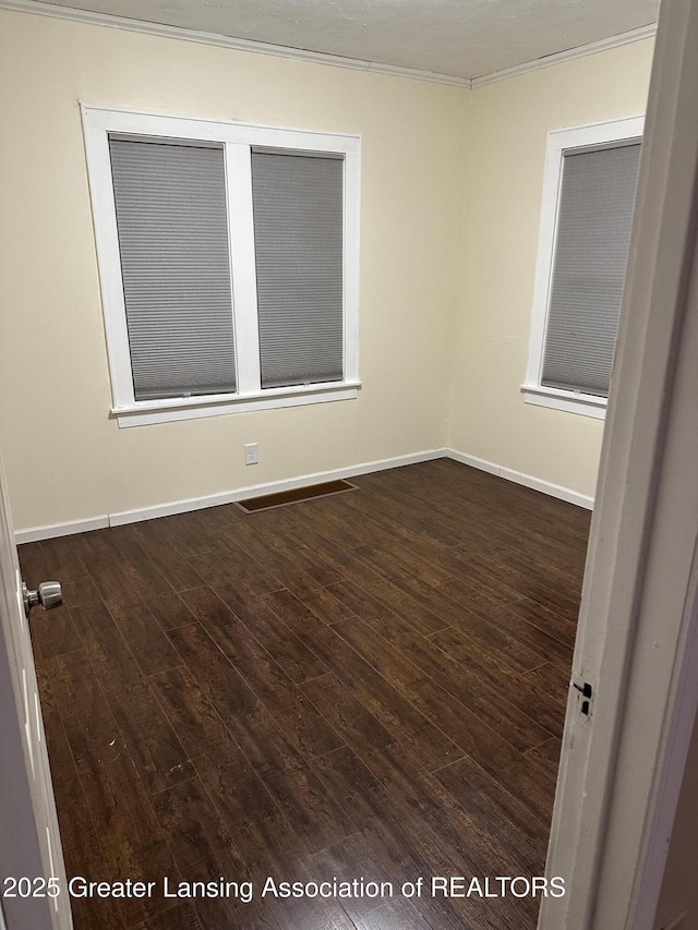 unfurnished room featuring ornamental molding, dark wood-type flooring, and baseboards