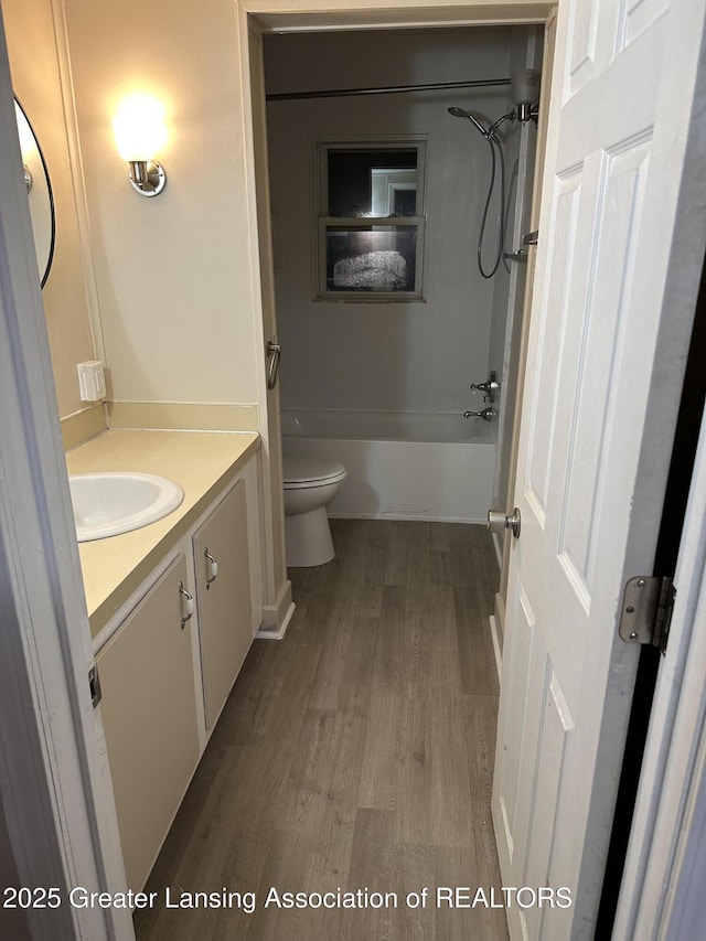 full bath featuring toilet, shower / bathing tub combination, wood finished floors, and vanity