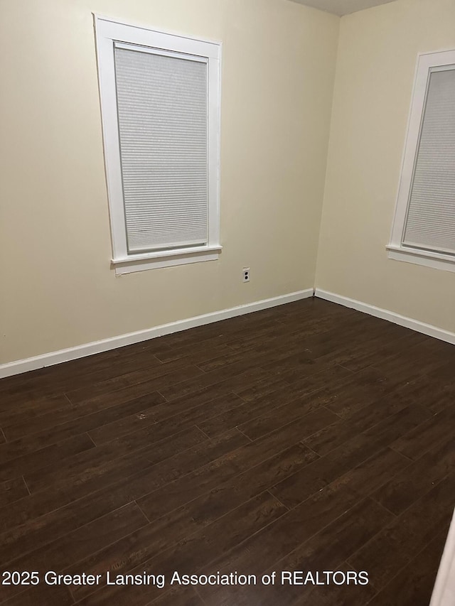 empty room with dark wood finished floors and baseboards