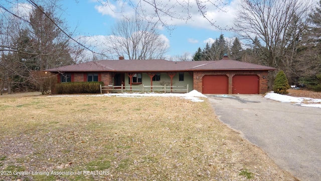 ranch-style home featuring a garage, aphalt driveway, a chimney, and a porch