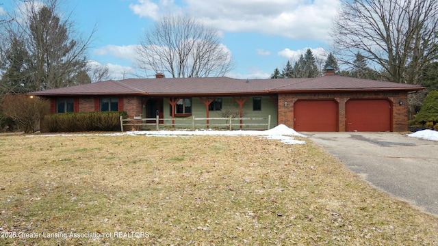 single story home with a garage, brick siding, a chimney, and aphalt driveway