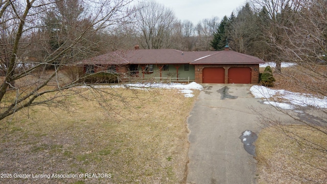 view of front of house with driveway, an attached garage, and a chimney