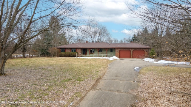 ranch-style home with a chimney, aphalt driveway, an attached garage, a front yard, and brick siding