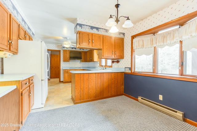 kitchen featuring a peninsula, light countertops, baseboard heating, brown cabinetry, and wallpapered walls