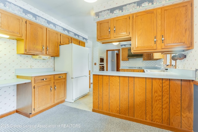 kitchen featuring freestanding refrigerator, light countertops, a sink, and wallpapered walls