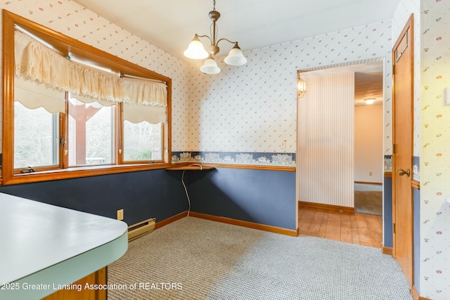 unfurnished dining area featuring baseboards, a baseboard heating unit, a notable chandelier, and wallpapered walls