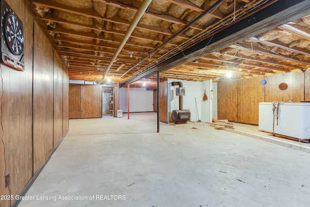 unfinished basement featuring fridge and wooden walls