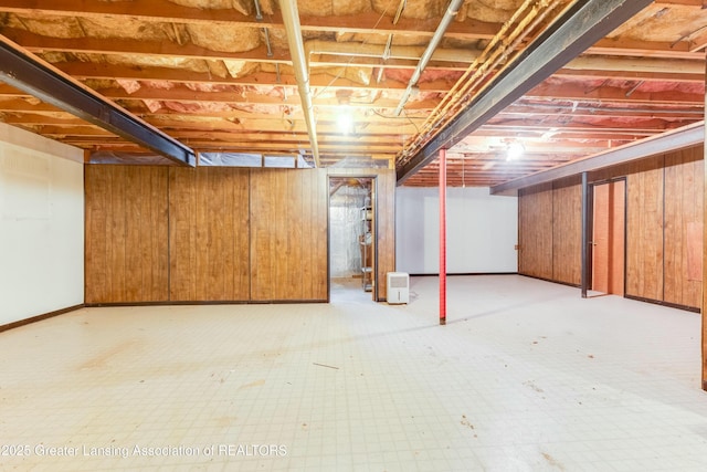 unfinished basement featuring wood walls and tile patterned floors