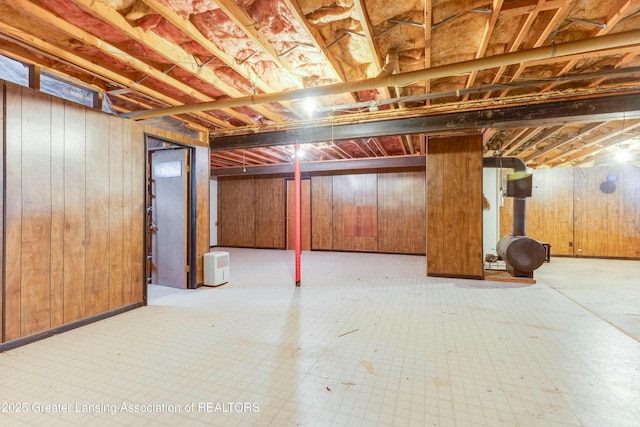 unfinished below grade area with wooden walls and tile patterned floors