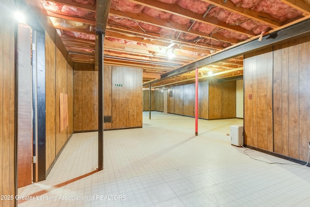 unfinished below grade area with wood walls and tile patterned floors