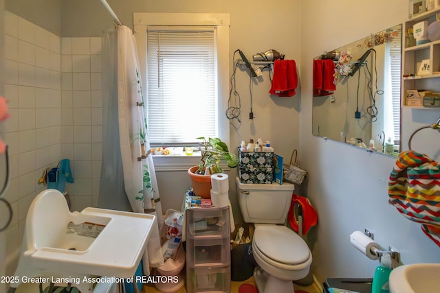 bathroom featuring toilet, a shower with curtain, and a sink