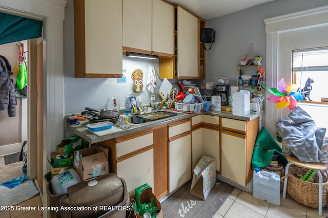 kitchen featuring light tile patterned floors, cream cabinets, and a sink