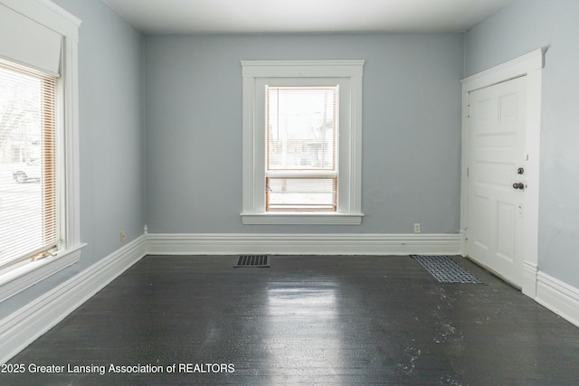 spare room featuring visible vents, baseboards, and wood finished floors